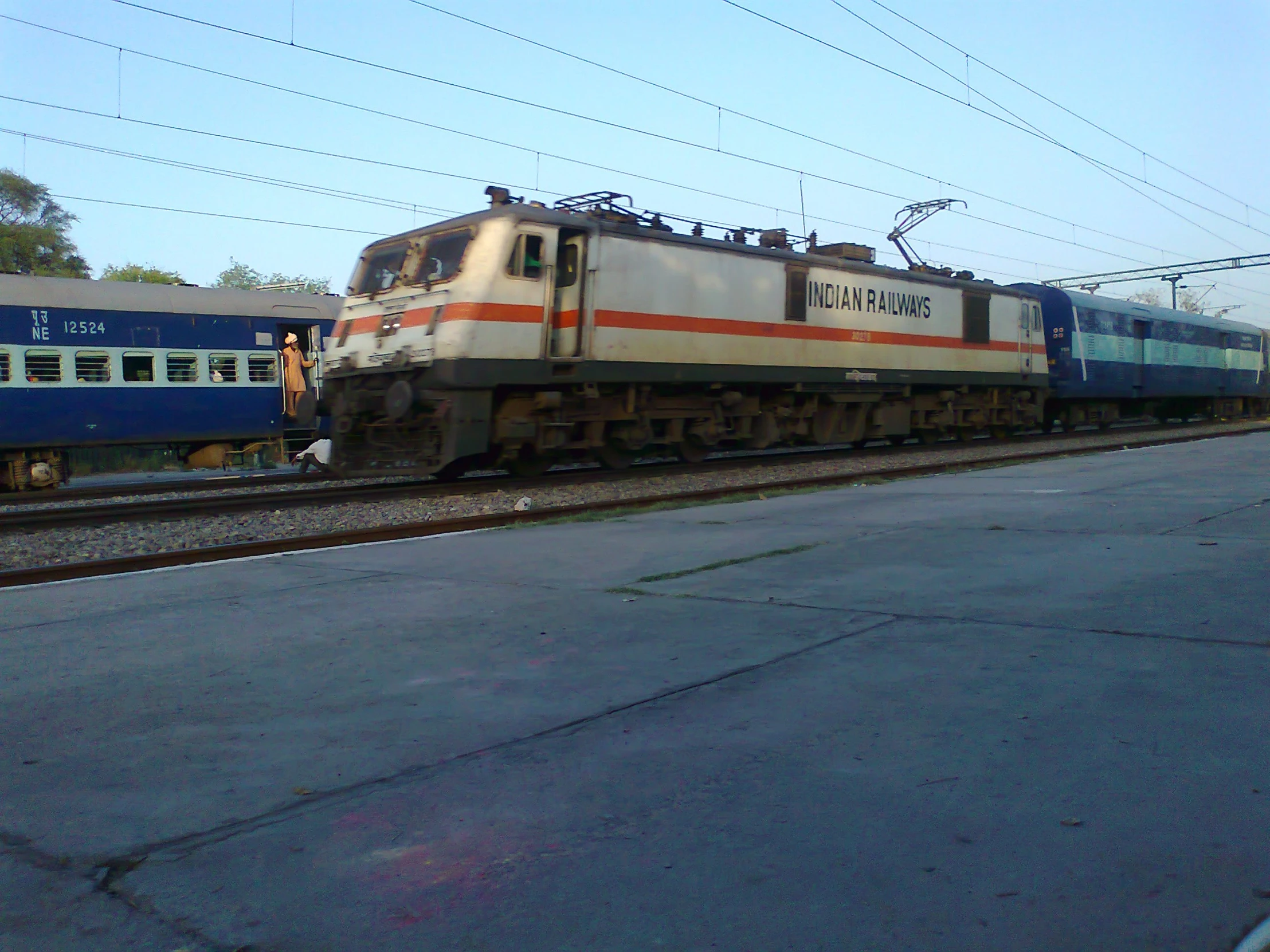 a train engine carrying carts down tracks past another train