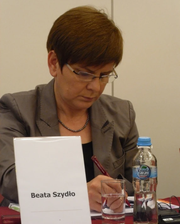 woman in glasses sitting at a table writing on paper