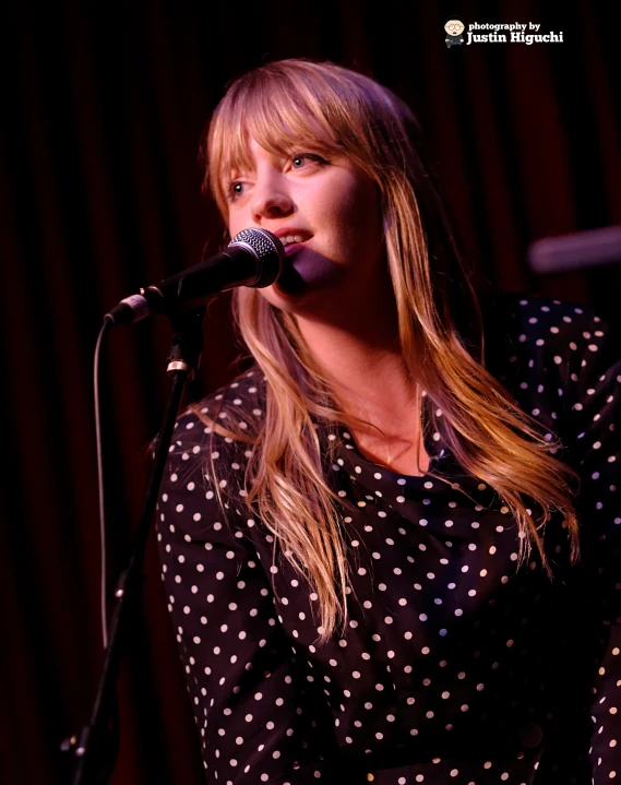 a girl singing with her hand on the microphone