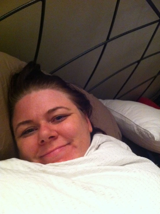 a woman in white bed under covers smiling