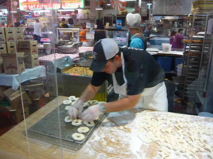 man making donuts in front of donut shop workers