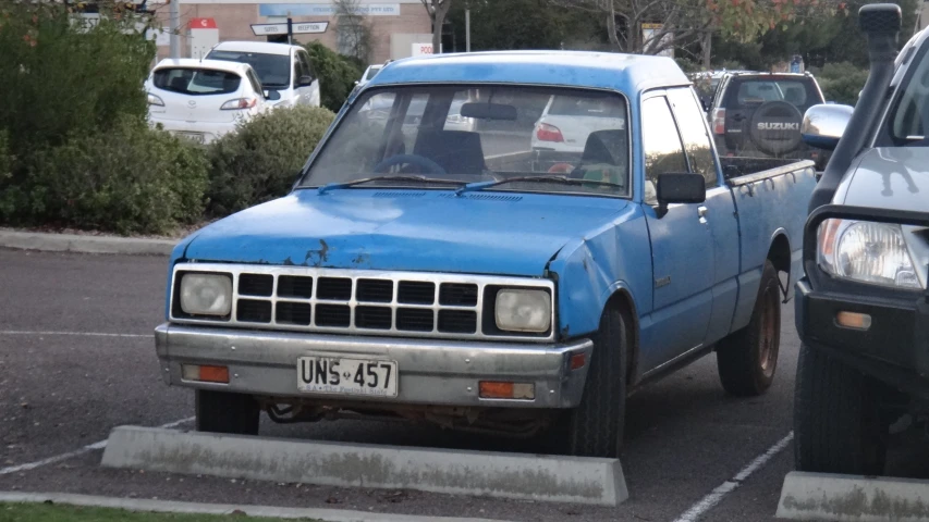 an old blue pickup truck parked in a parking space