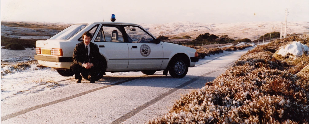 a policeman with his van on the side of a snowy road