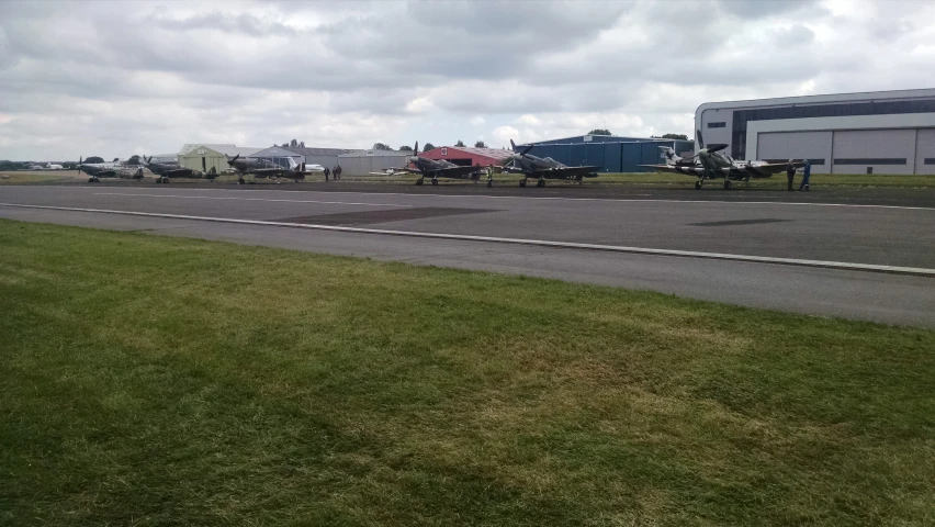 many planes parked in a grass field by the runway