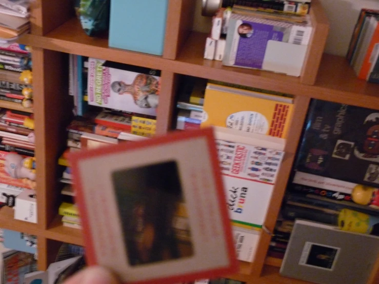 someone is holding up a book in front of a book case