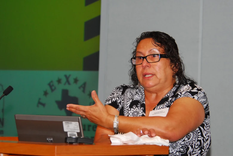 a woman speaking in front of a microphone and a laptop