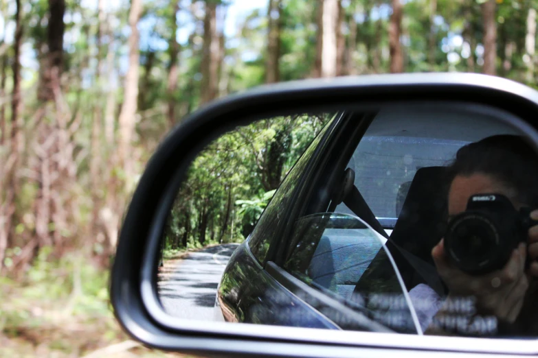 the car is driving down the road and taking pictures in the side mirror