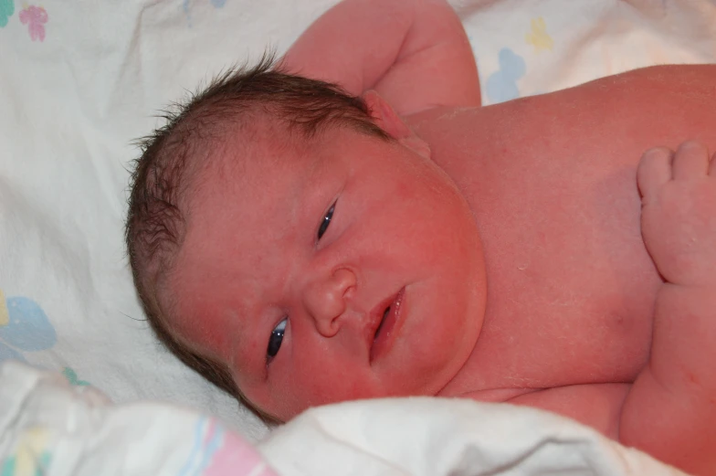 a newborn baby on a blanket and with one hand on the belly