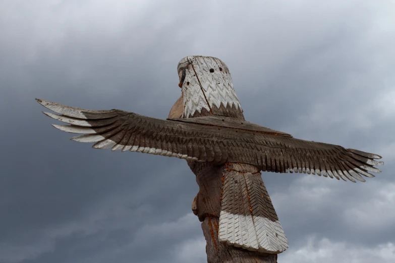 a tall wooden sculpture of an owl with wings extended