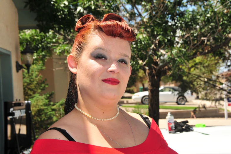 woman in red with red dyed hair poses for a po