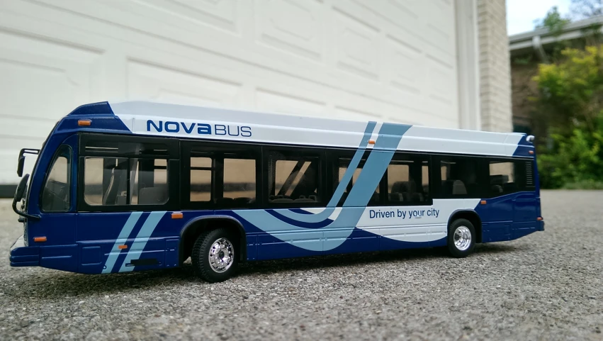 a blue and white bus is parked on a concrete road