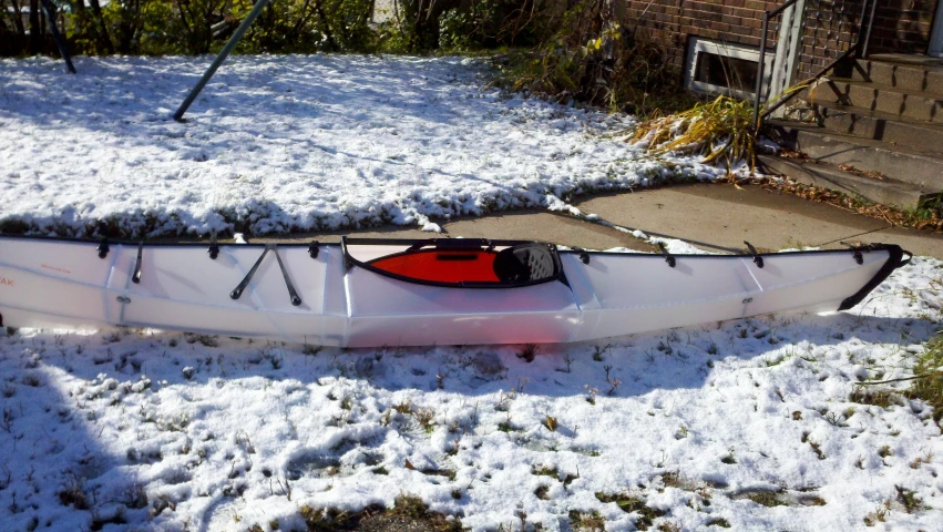 the canoe is laying in the snow near the house