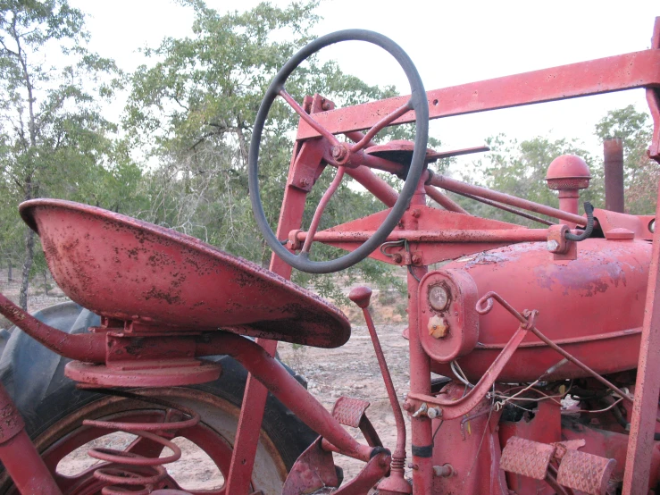 an old rusted out red tractor in the grass