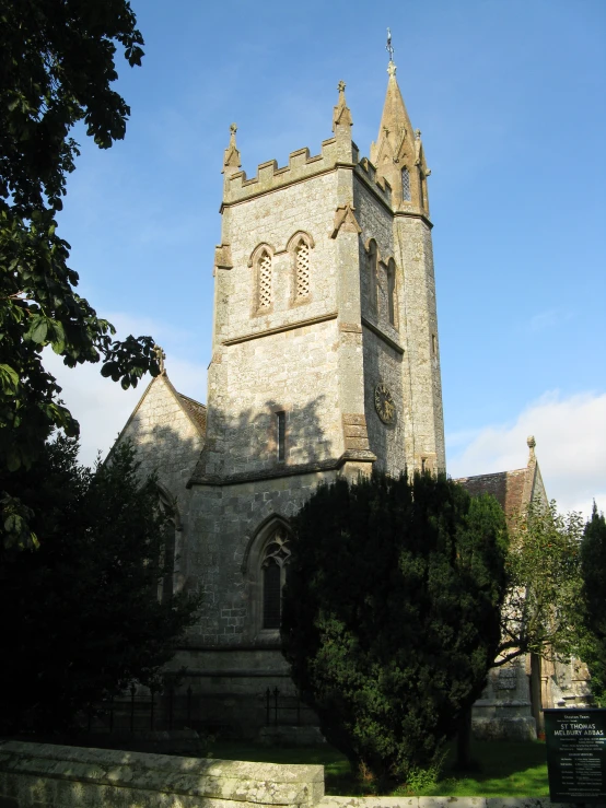 an old church with tower, some trees and grass on the ground