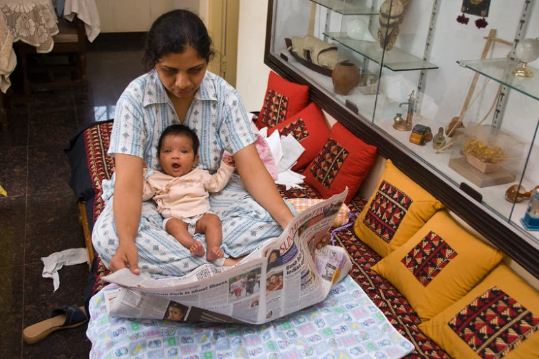 a woman with a baby looking through a magazine