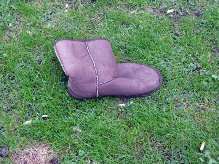 an old brown chair sits alone in the grass