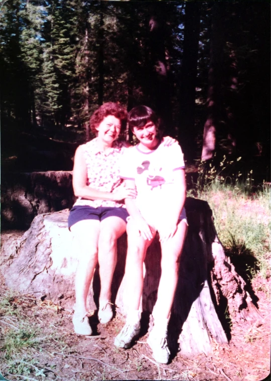 two women that are sitting on a large rock