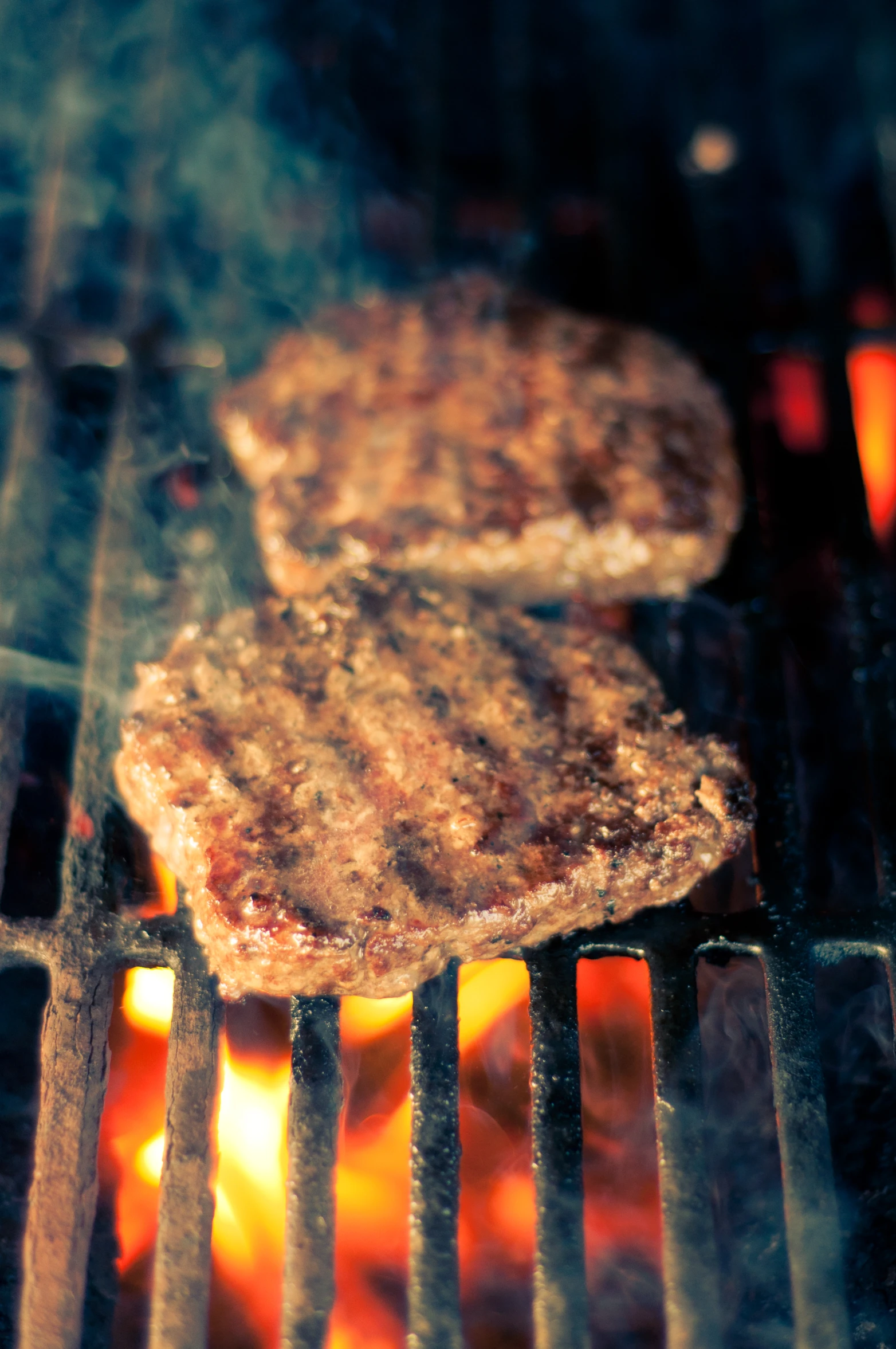 hamburger burgers cooking on a grill with flames