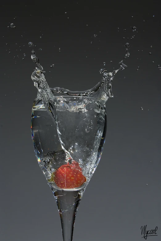 a strawberry splashing into a martini glass with ice