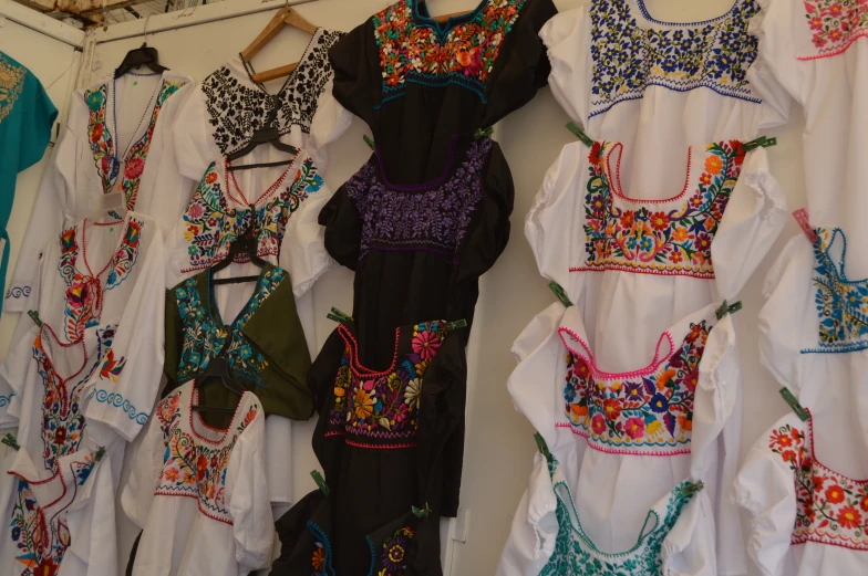 several mexican dresses hanging on a wall