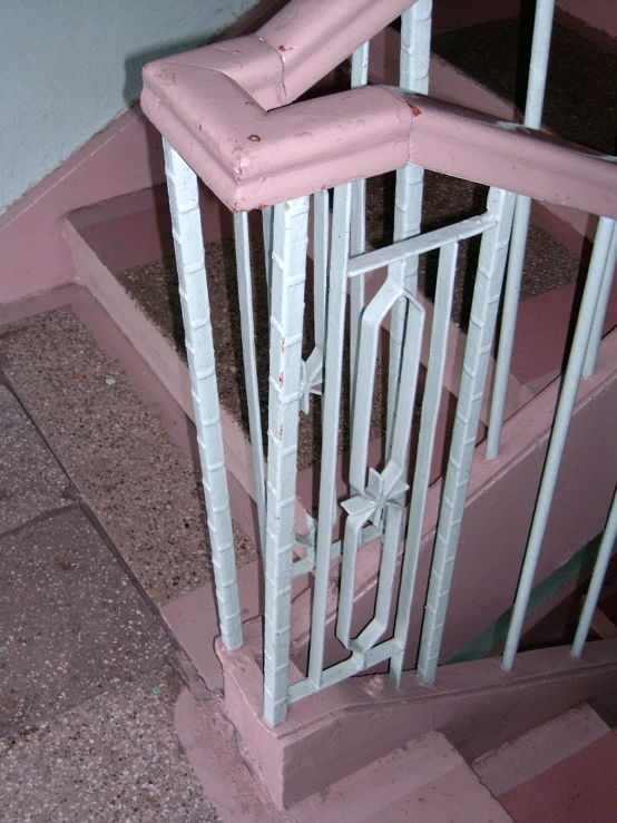 some pink steps and a white railing near some wall