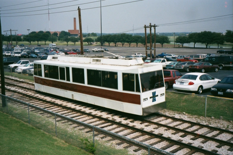 an old style tram is on the tracks in a parking lot