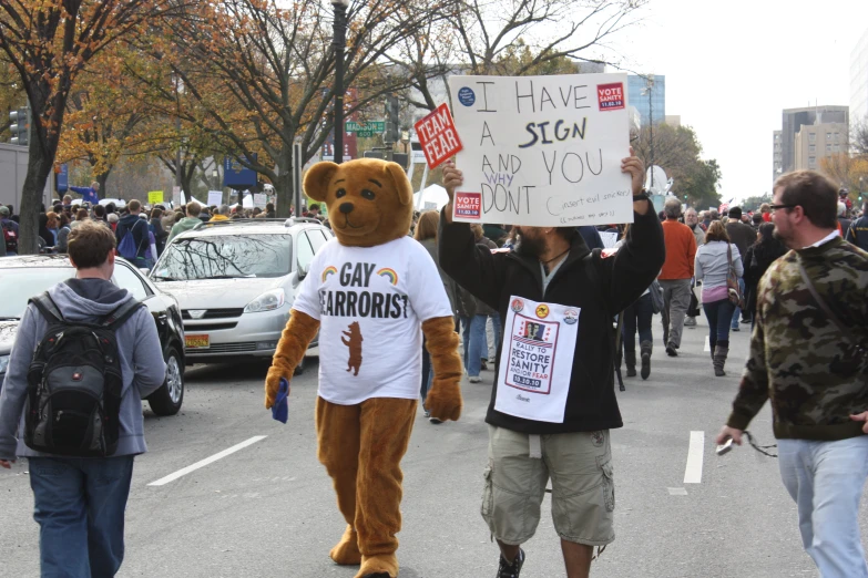 a person dressed up as a bear and holding signs