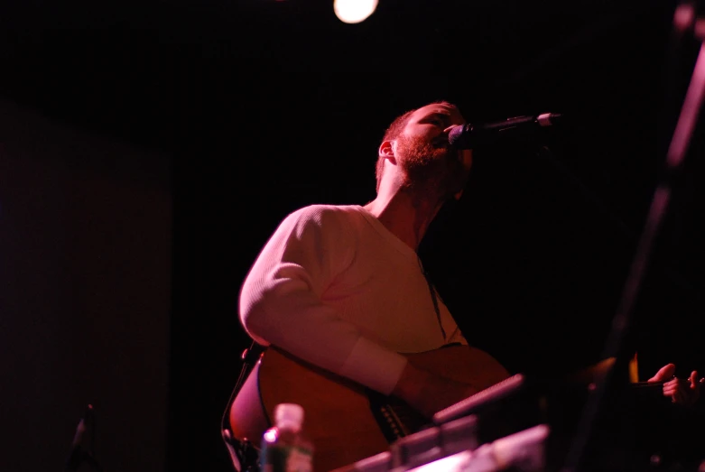 the man sings into the microphone while playing a guitar