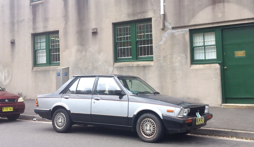 a car parked outside a grey building on the street