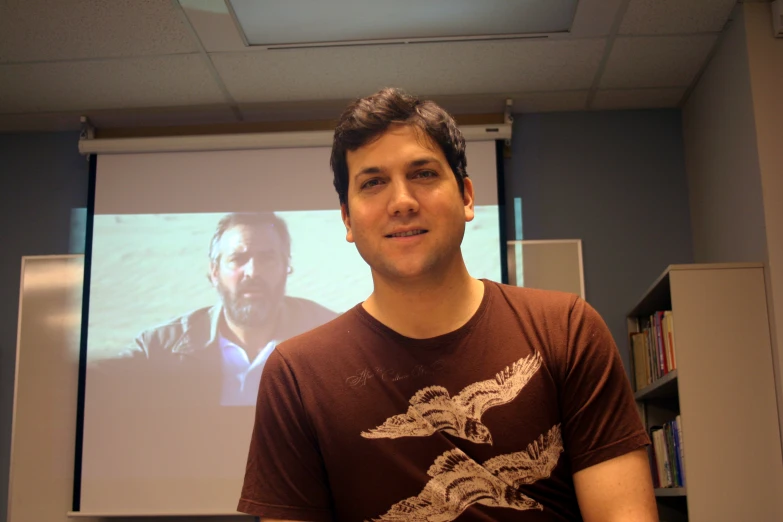 a young man standing in front of a projection