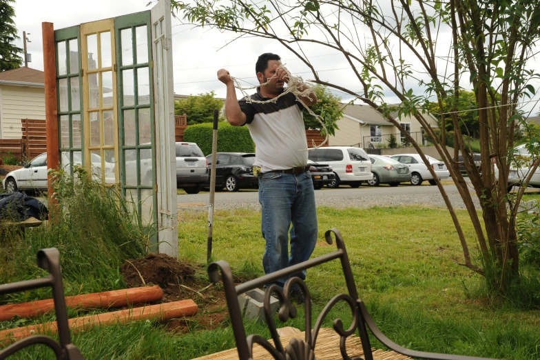 a man is holding up some plants in the yard