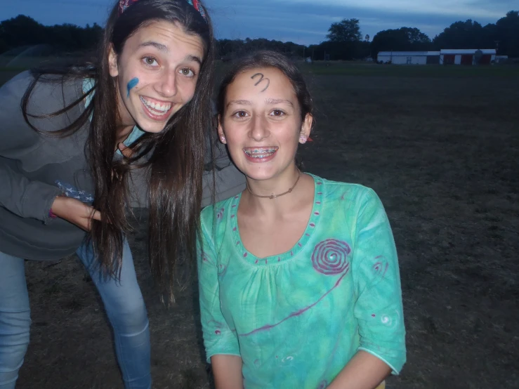 two girls standing in the grass with a dark sky in the background