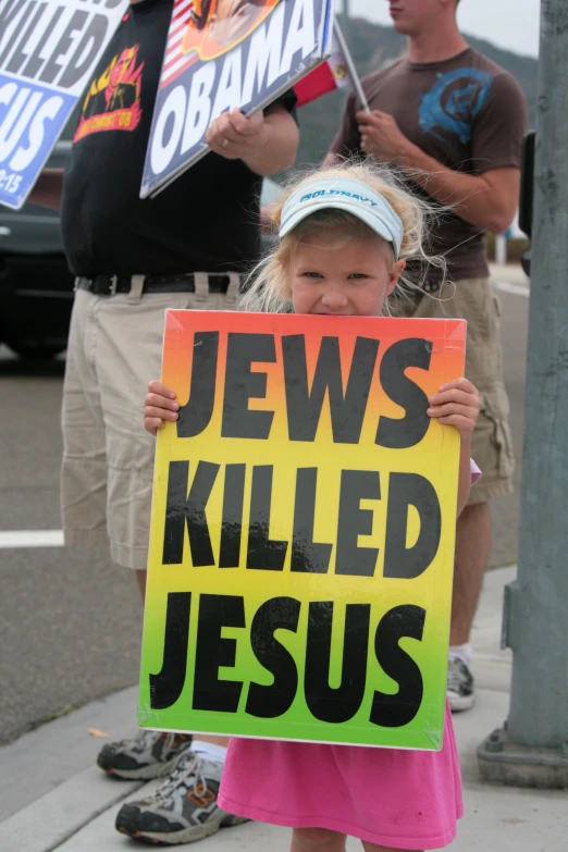 a little girl standing on a sidewalk holding up a sign