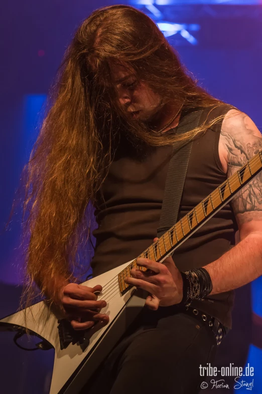 a person that has long hair playing the guitar