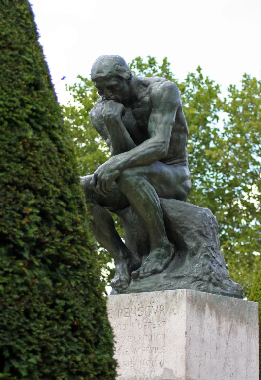 there is a statue in the shape of a sitting thinker