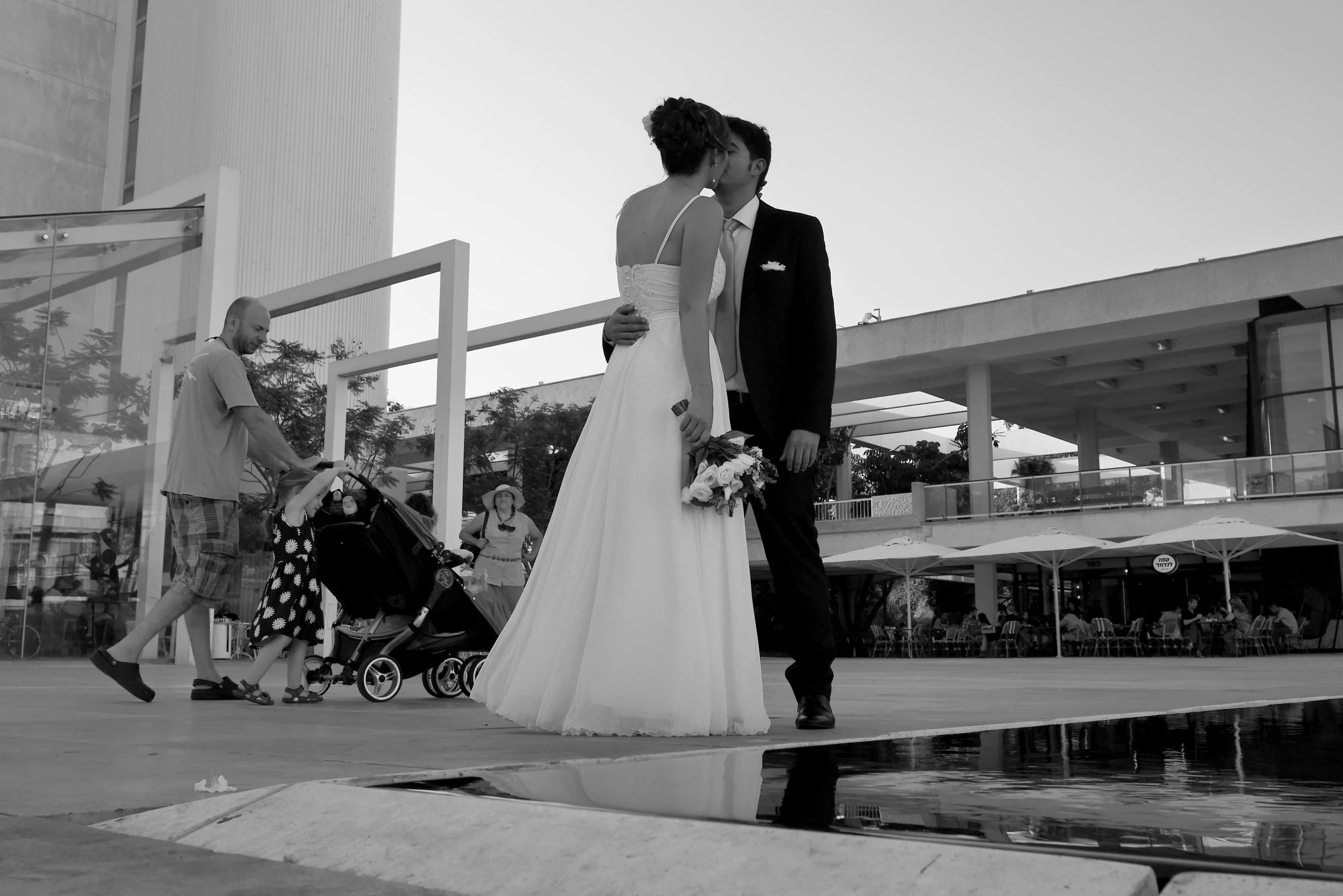 a bride and groom stand next to each other on a sidewalk