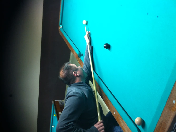 a man is leaning over to pick up a pool ball