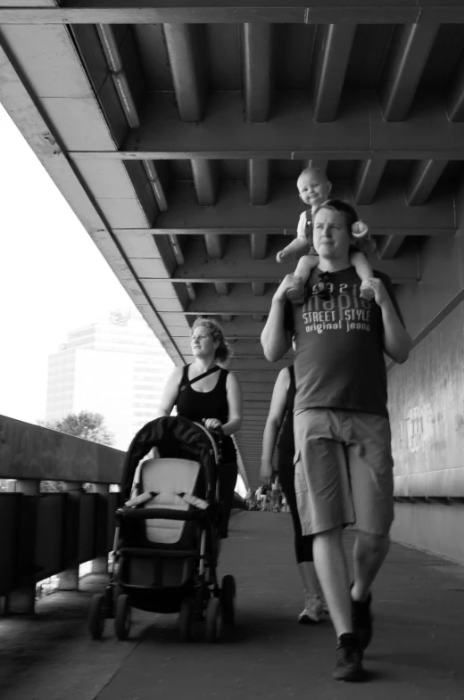 an image of man with baby on his shoulders walking down the road
