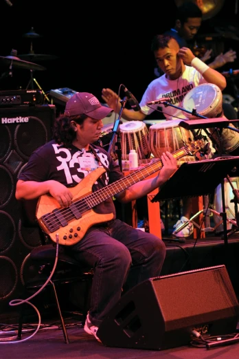 a man plays an electric guitar as others play musical instruments in the background