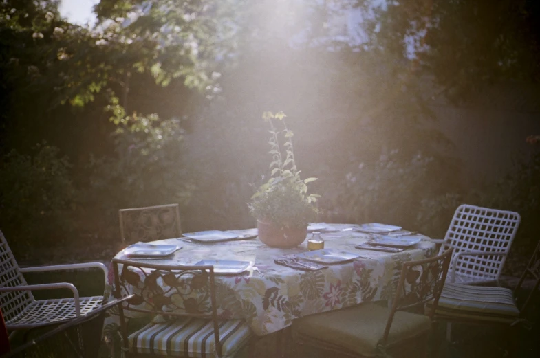 a table in the sun is set with three chairs