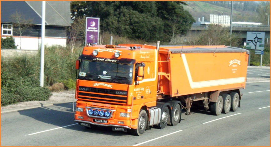 an orange dump truck driving down the street