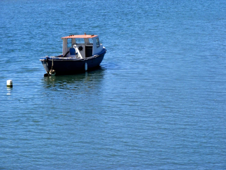 a blue boat sailing on top of a large body of water