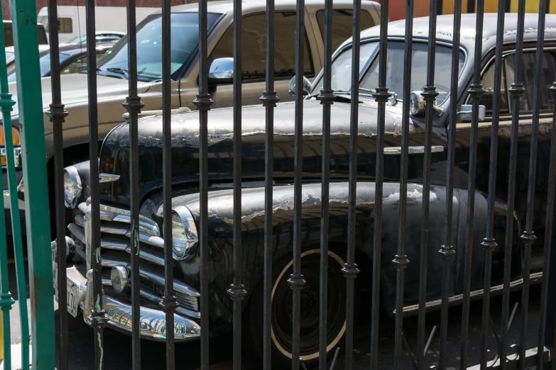 a row of classic cars behind bars on a street