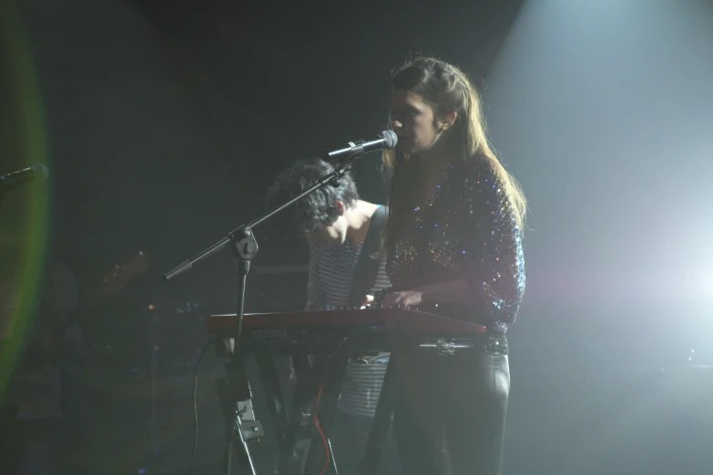 a woman standing in front of a microphone and a keyboard