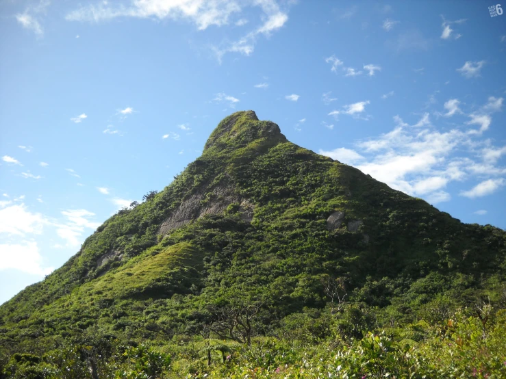 a large mountain with green grass on the side