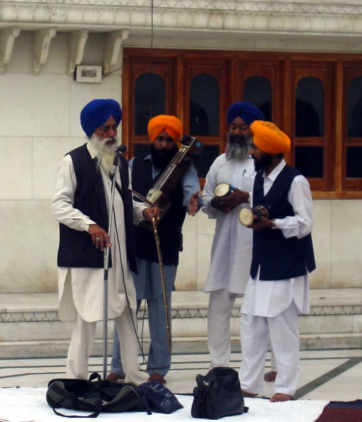 a group of men in orange turbans are standing by some music