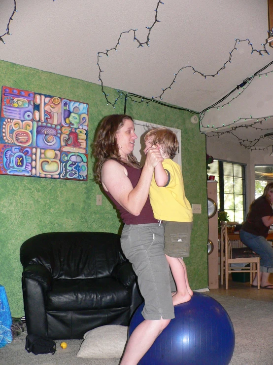 a woman plays with a child on a yoga ball