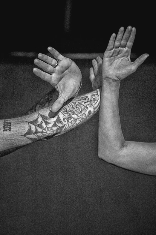 hands outstretched in the air with tattoos on them