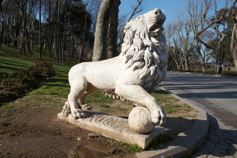 a marble lion statue is in the middle of a grass field