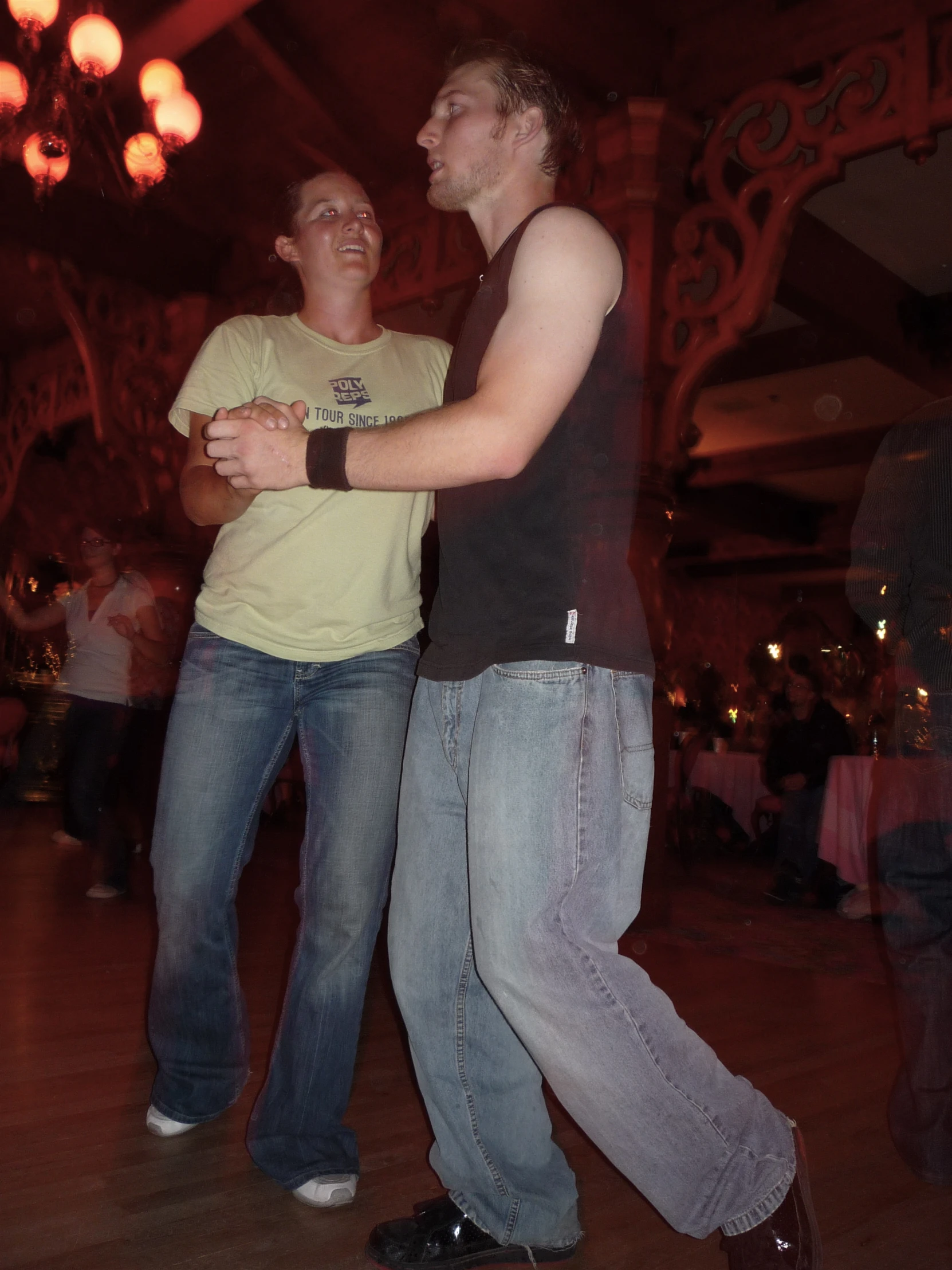 two people with jeans and a tan shirt are dancing